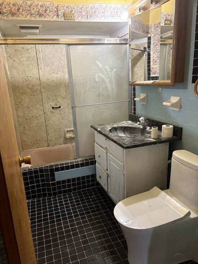 bathroom with tile walls, vanity, a shower, tile patterned floors, and toilet