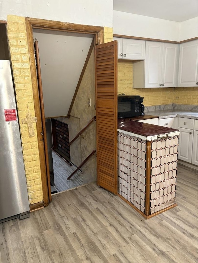 kitchen featuring stainless steel fridge, light hardwood / wood-style floors, and white cabinets