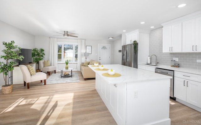 kitchen with white cabinets, appliances with stainless steel finishes, a center island, and sink