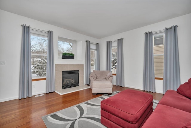 living room with wood-type flooring and a tiled fireplace