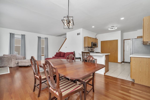 dining space with a notable chandelier and light wood-type flooring