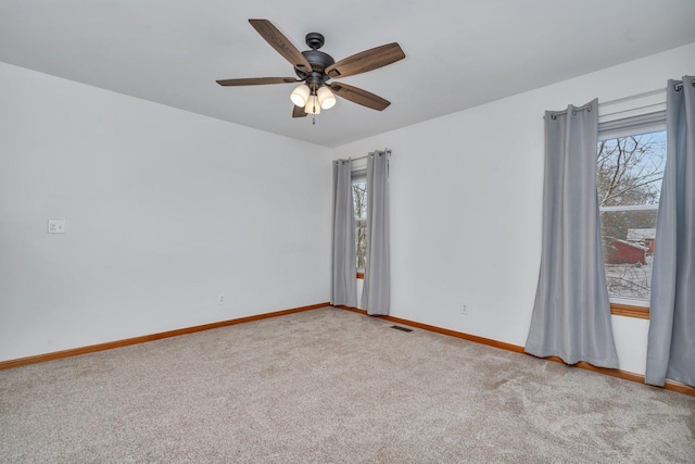 empty room featuring plenty of natural light, ceiling fan, and light carpet