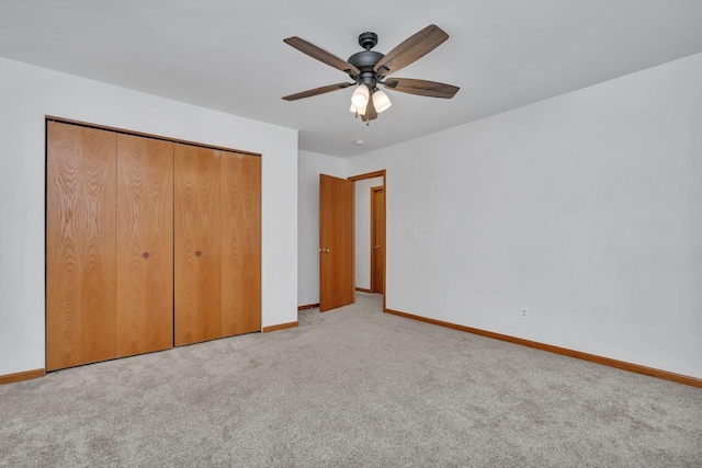 unfurnished bedroom featuring ceiling fan, light colored carpet, and a closet