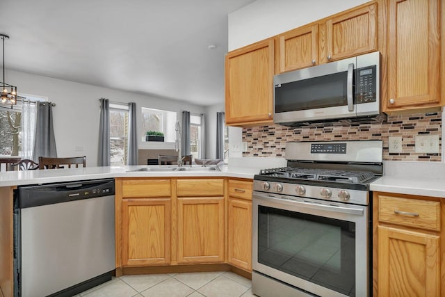 kitchen with tasteful backsplash, stainless steel appliances, sink, light tile patterned floors, and decorative light fixtures