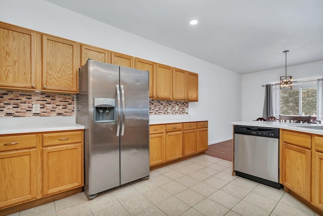 kitchen featuring backsplash, stainless steel appliances, a notable chandelier, hanging light fixtures, and light tile patterned flooring