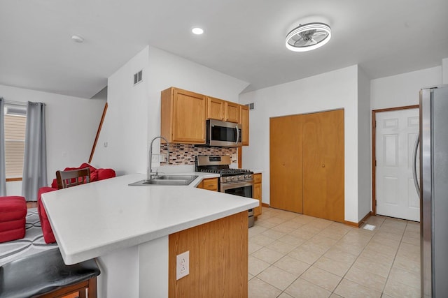 kitchen with sink, appliances with stainless steel finishes, tasteful backsplash, a kitchen bar, and kitchen peninsula