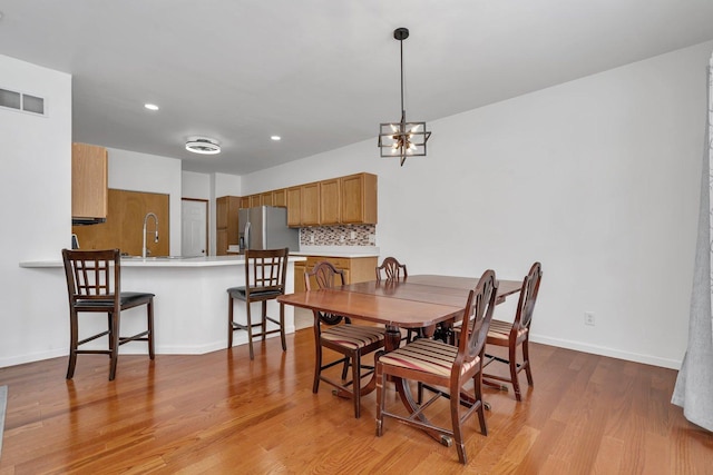 dining space featuring a chandelier, light hardwood / wood-style flooring, and sink