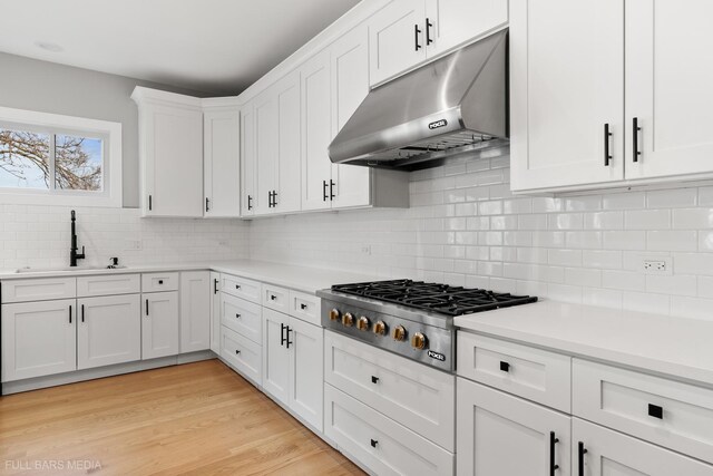 kitchen featuring backsplash, white cabinetry, stainless steel gas stovetop, and sink