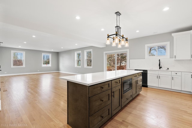 kitchen featuring tasteful backsplash, built in microwave, sink, white cabinetry, and hanging light fixtures