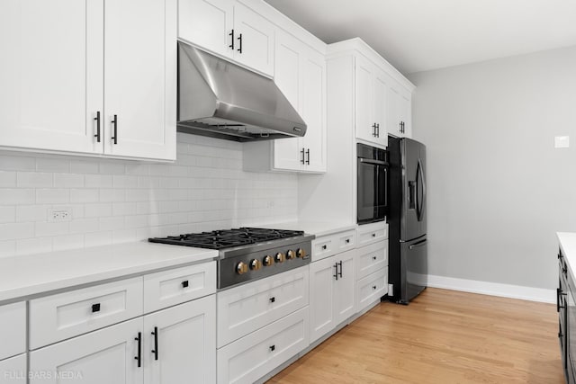 kitchen with white cabinets, stainless steel appliances, light hardwood / wood-style flooring, and tasteful backsplash