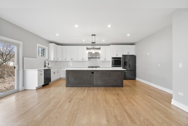 kitchen featuring pendant lighting, white cabinets, light wood-type flooring, appliances with stainless steel finishes, and a kitchen island