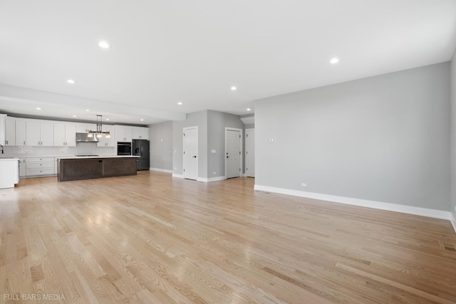 unfurnished living room featuring light wood-type flooring and sink