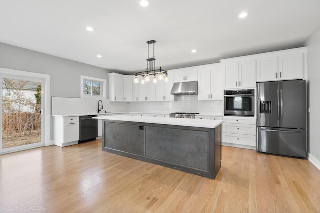 kitchen featuring pendant lighting, white cabinets, light wood-type flooring, and appliances with stainless steel finishes