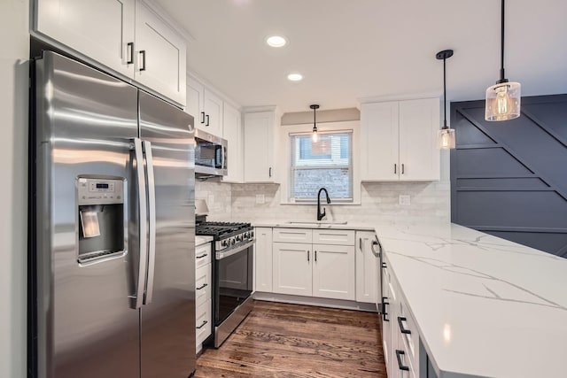 kitchen featuring hanging light fixtures, white cabinetry, sink, and stainless steel appliances