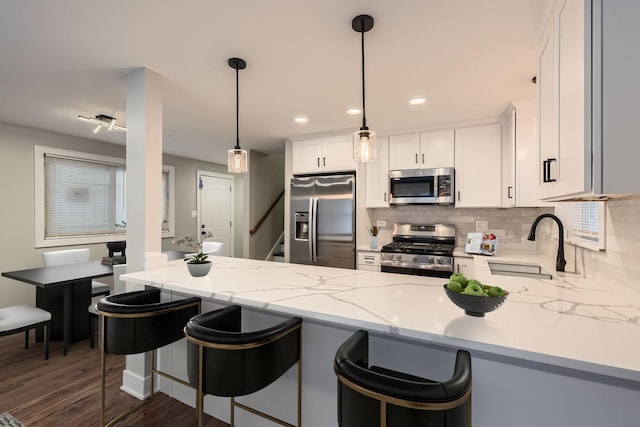 kitchen with pendant lighting, white cabinets, sink, kitchen peninsula, and stainless steel appliances