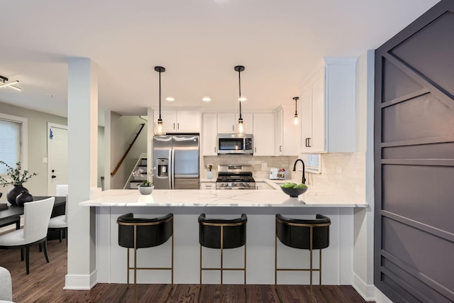 kitchen with a kitchen breakfast bar, dark hardwood / wood-style flooring, white cabinetry, and appliances with stainless steel finishes