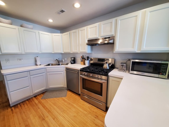 kitchen featuring white cabinetry, sink, stainless steel appliances, and light hardwood / wood-style floors