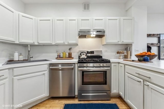 kitchen with appliances with stainless steel finishes, light hardwood / wood-style flooring, white cabinetry, and sink