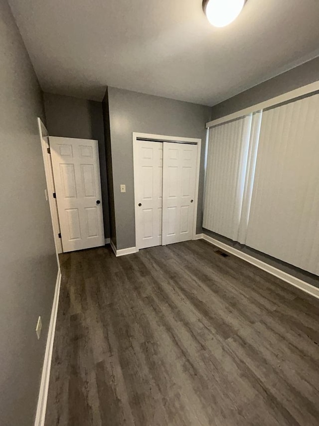 unfurnished bedroom with a closet and dark wood-type flooring