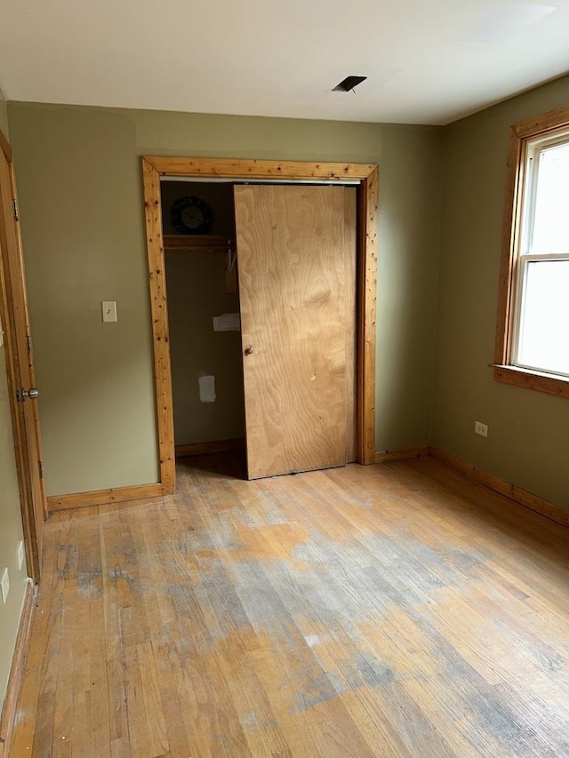 unfurnished bedroom with light wood-type flooring and a closet