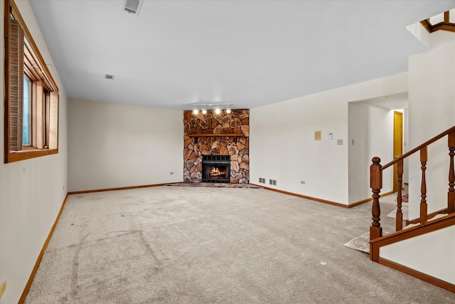 unfurnished living room featuring carpet and a stone fireplace