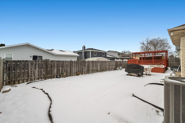 snowy yard with central AC unit, a wooden deck, and a jacuzzi