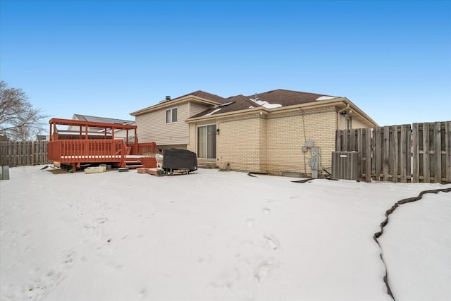 snow covered back of property featuring a deck