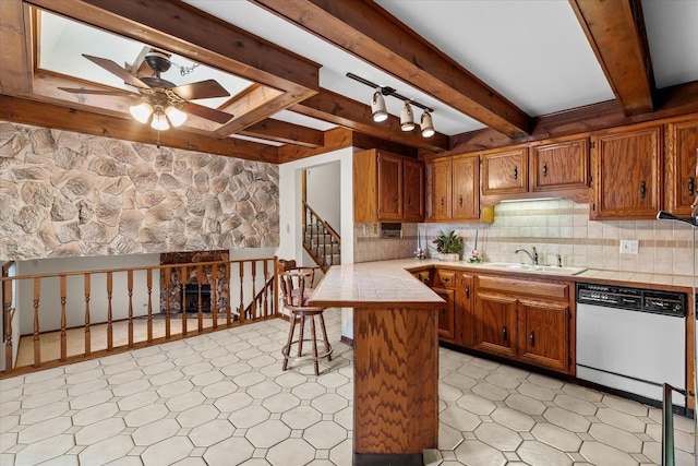 kitchen featuring ceiling fan, tasteful backsplash, dishwasher, sink, and tile counters