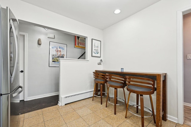 dining area with bar area and a baseboard heating unit