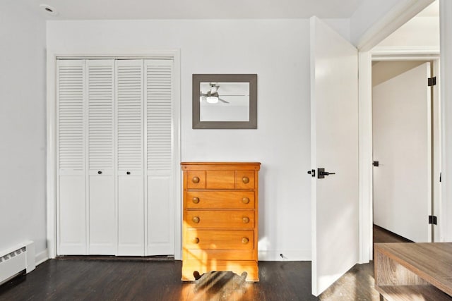 interior space with dark hardwood / wood-style flooring, a baseboard radiator, and a closet