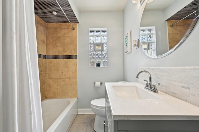 full bathroom featuring toilet, vanity, tiled shower / bath combo, hardwood / wood-style floors, and backsplash