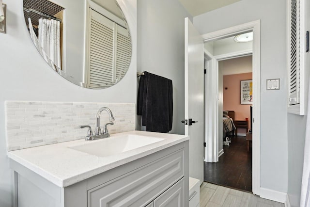 bathroom featuring hardwood / wood-style flooring, vanity, and backsplash