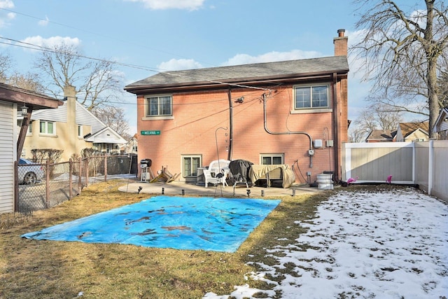 snow covered rear of property featuring a yard and a patio