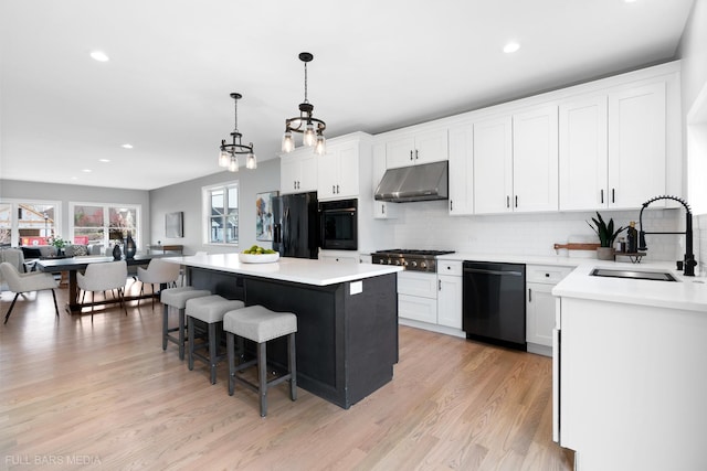 kitchen featuring white cabinets, sink, a kitchen island, and black appliances