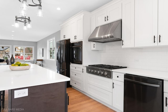 kitchen featuring light hardwood / wood-style flooring, decorative light fixtures, decorative backsplash, white cabinets, and appliances with stainless steel finishes