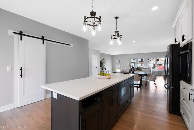 kitchen featuring black fridge, a barn door, white cabinetry, and built in microwave