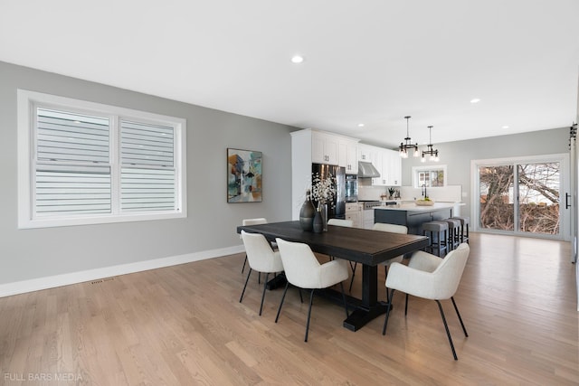 dining area with an inviting chandelier and light hardwood / wood-style flooring