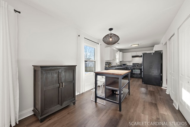 kitchen featuring pendant lighting, sink, black appliances, white cabinets, and dark hardwood / wood-style flooring