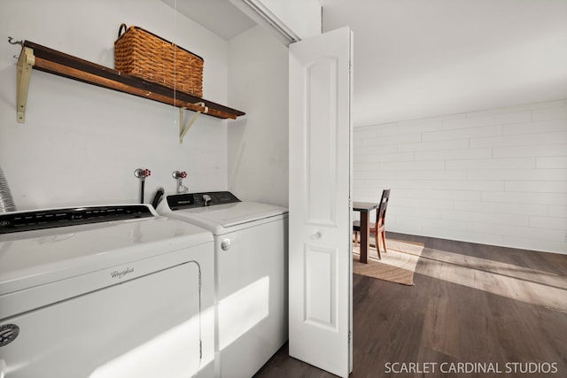 laundry room with dark hardwood / wood-style flooring, washer and clothes dryer, and brick wall