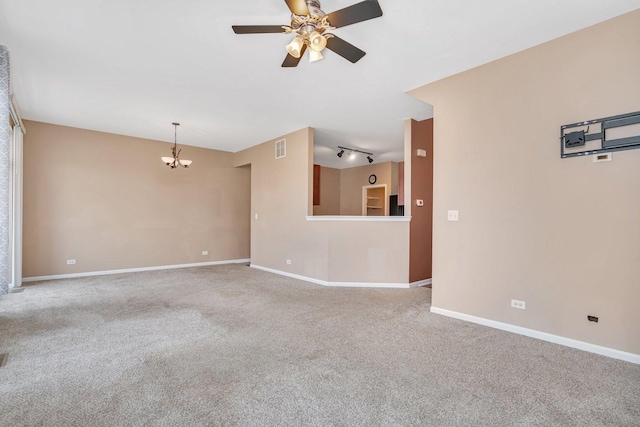 carpeted empty room with ceiling fan with notable chandelier and rail lighting