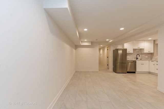 kitchen featuring decorative backsplash, stainless steel appliances, white cabinetry, and sink