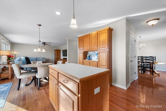 kitchen featuring a notable chandelier, light hardwood / wood-style floors, hanging light fixtures, and a kitchen island