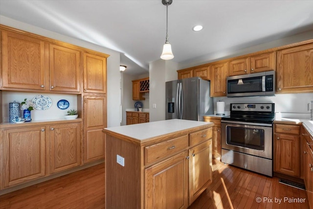 kitchen featuring stainless steel appliances, a center island, hanging light fixtures, and light hardwood / wood-style flooring