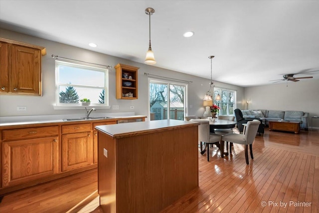 kitchen featuring sink, decorative light fixtures, a center island, and light wood-type flooring