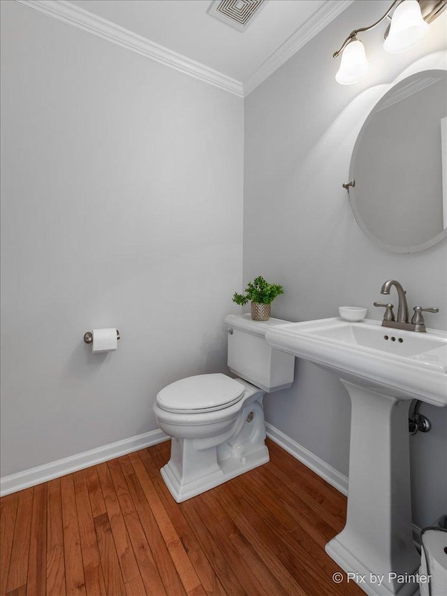 bathroom with hardwood / wood-style flooring, crown molding, sink, and toilet