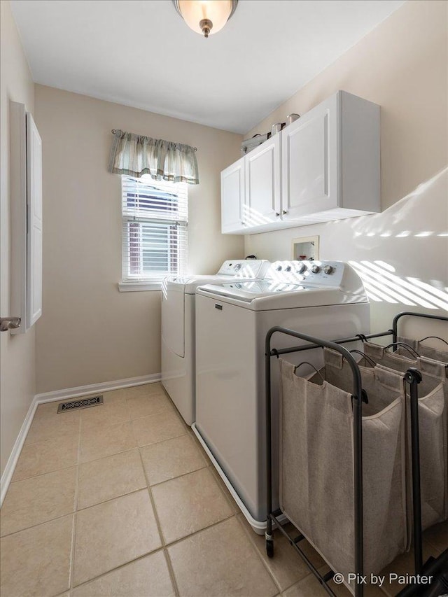 washroom with cabinets, washer and dryer, and light tile patterned floors