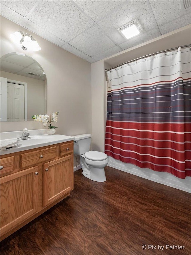 bathroom featuring a drop ceiling, vanity, hardwood / wood-style flooring, and toilet