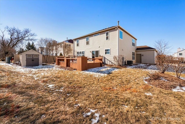 snow covered property with a wooden deck, central AC unit, and a storage shed