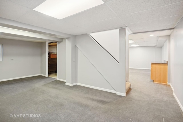 basement with a paneled ceiling and carpet flooring