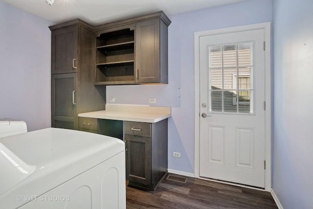 washroom with dark wood-type flooring, washer and dryer, and cabinets